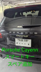 Rear view of a black Porsche Cayenne S with a Japanese license plate, parked inside a garage or tented area.