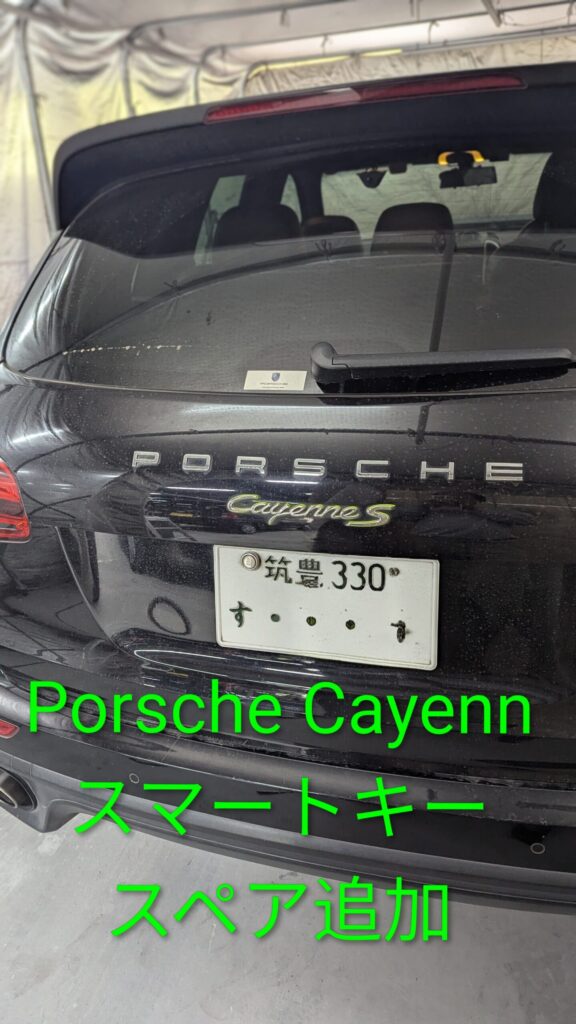 Rear view of a black Porsche Cayenne S with a Japanese license plate, parked inside a garage or tented area.