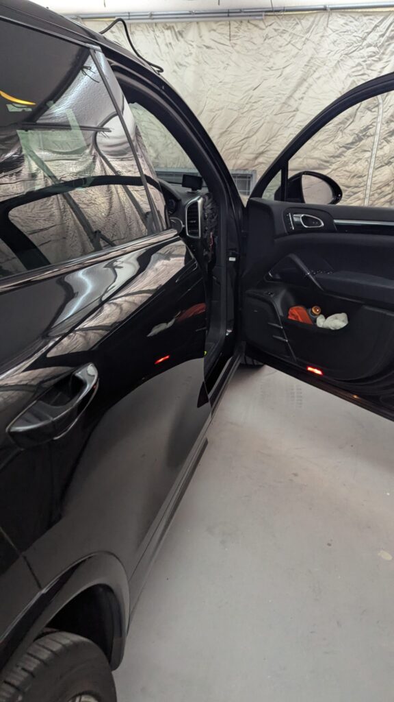 Black SUV with both front and rear passenger doors open, parked in a garage with a light-colored backdrop. - 車専門鍵店カーロック 施工実績・鍵作成